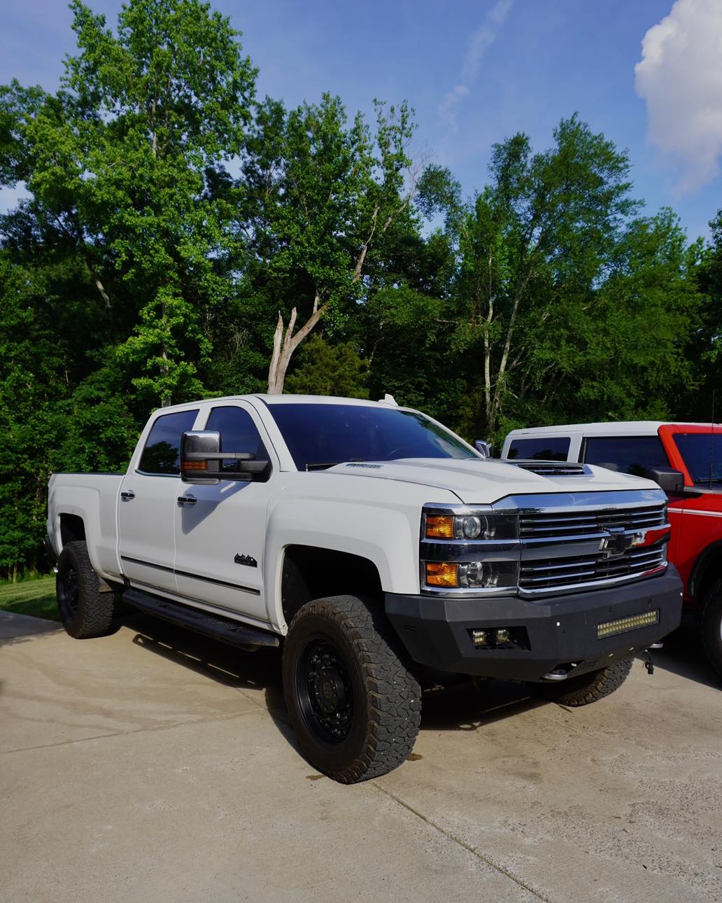 White Chevy Silverado 2500HD after exterior detail — clean chrome grille, dressed tires, glossy white paint in a residential driveway